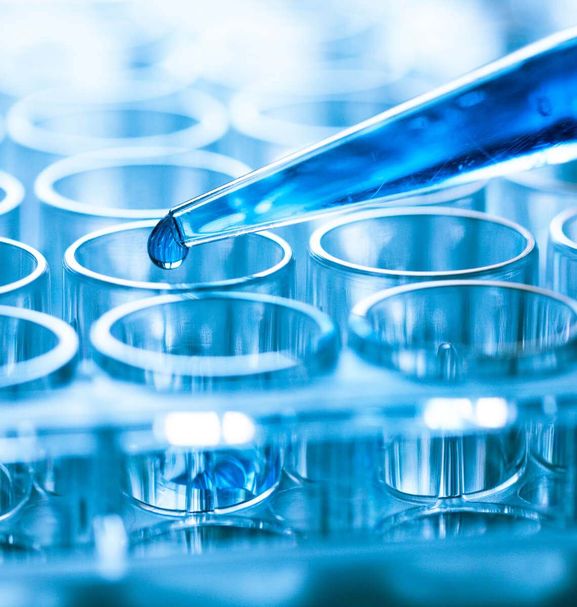 Close-up image of a pipette dropping liquid into a vial.